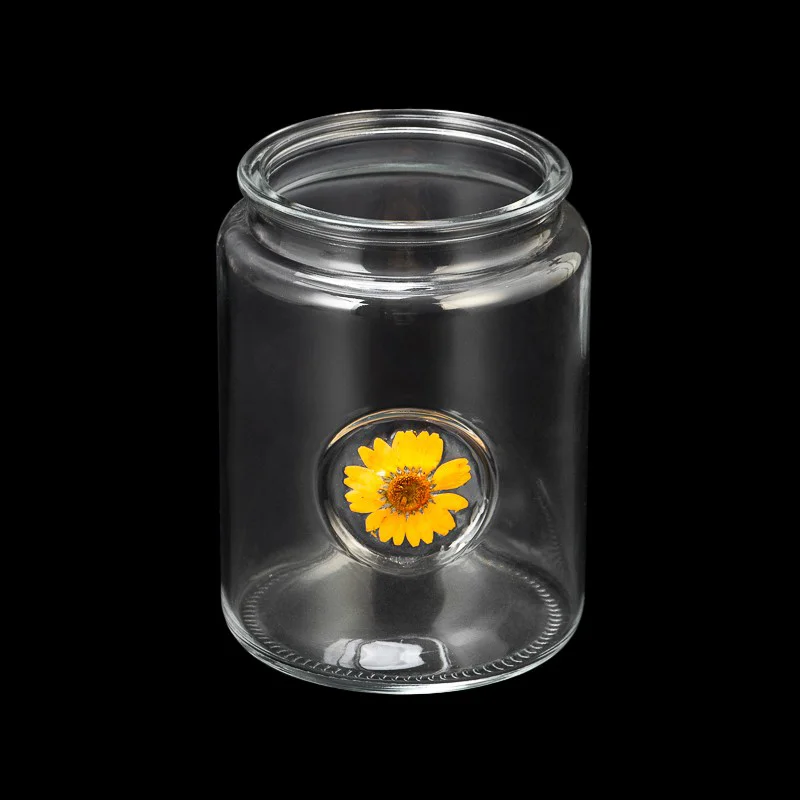 glass candle jar with dry flower attached in glass wall