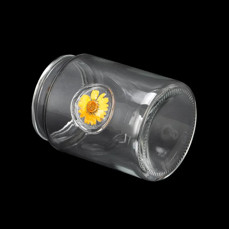 glass candle jar with dry flower attached in glass wall