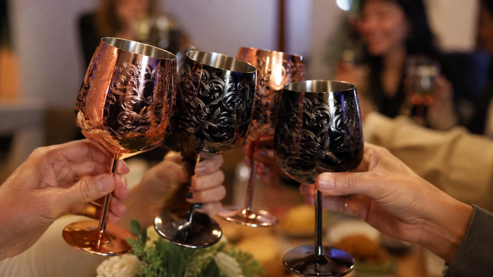 Premium etched stainless steel wine glasses raised for a toast at a dinner party