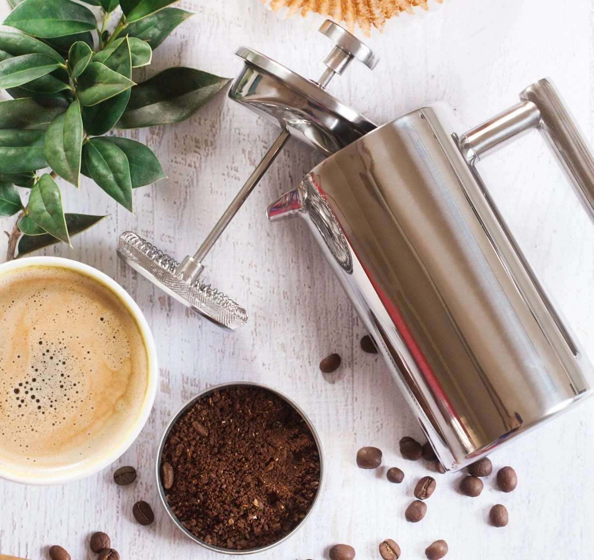 Coarse-ground coffee beside a stainless steel French press, showing a suitable grind size for French press brewing.