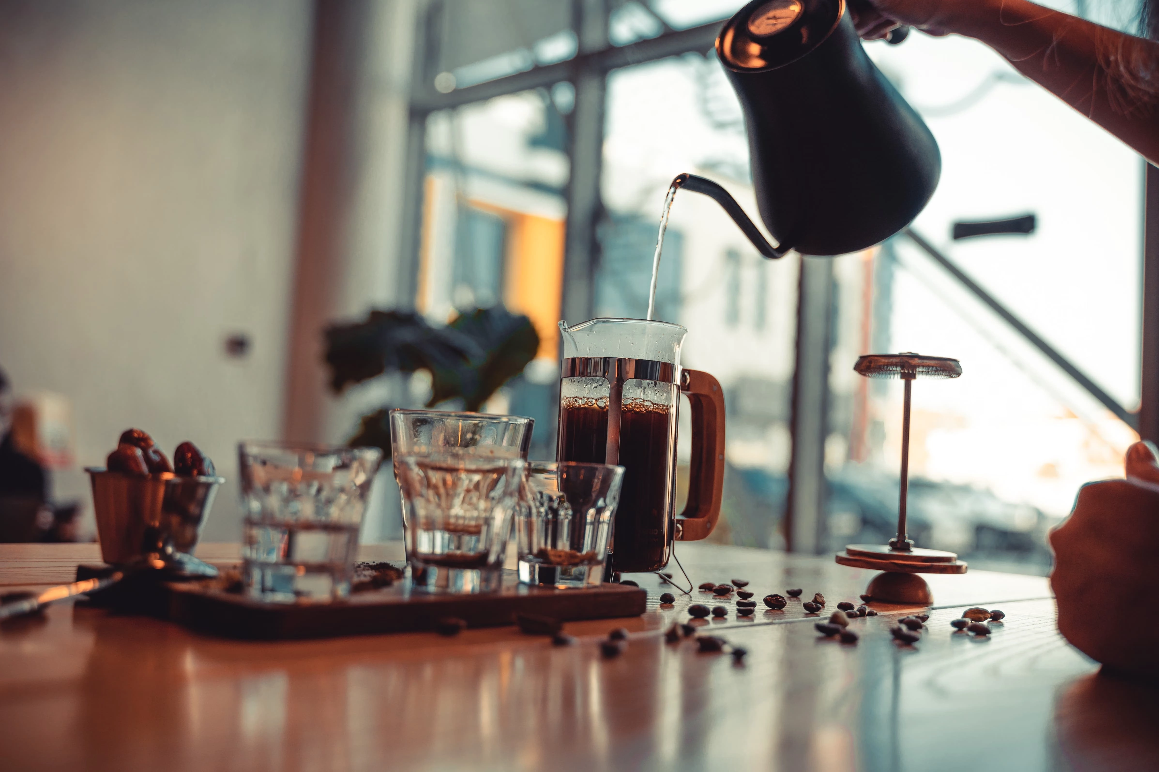 Hot water being poured from a gooseneck kettle into a French press during coffee brewing