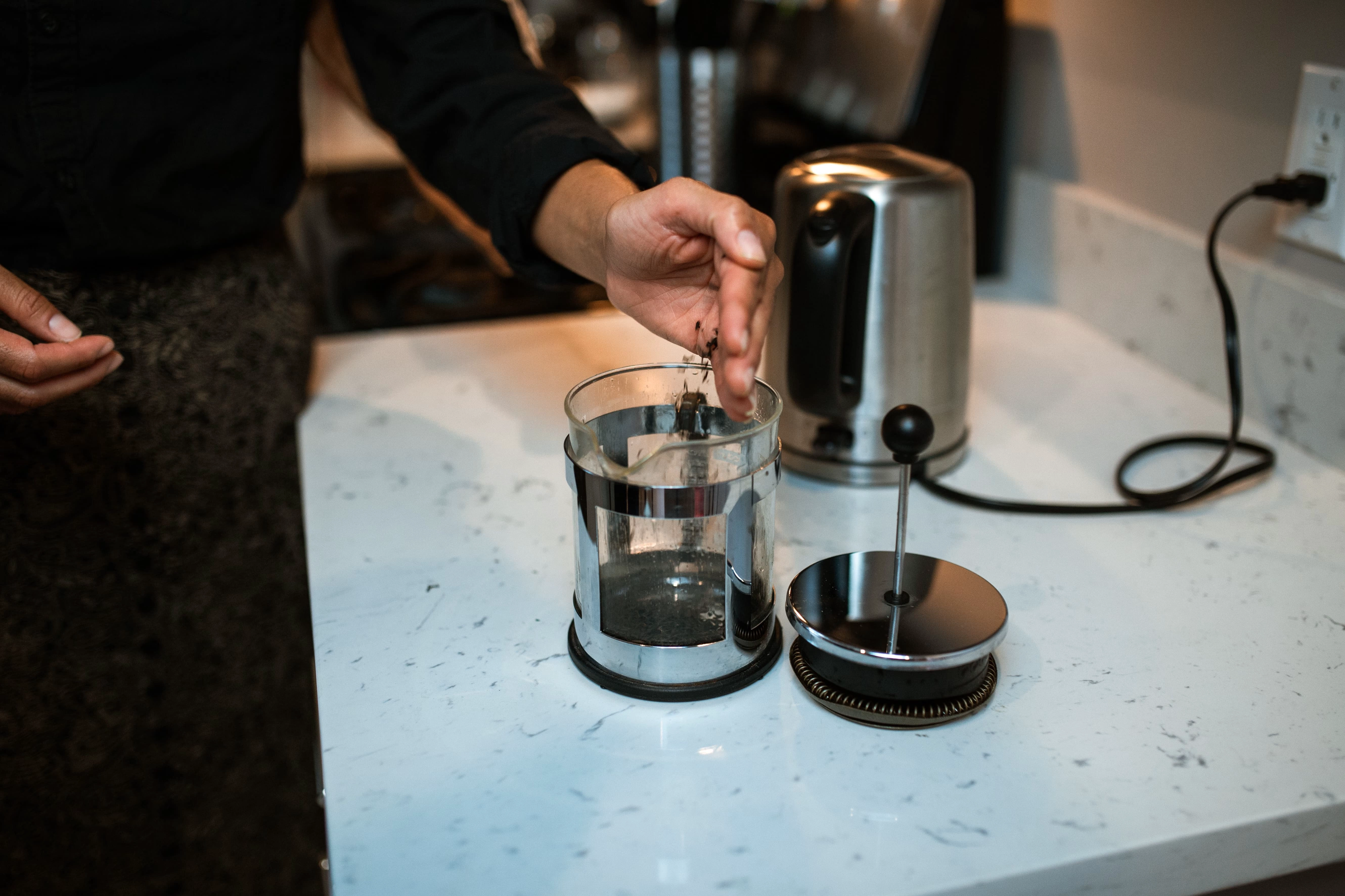 French press coffee preparation with the filter plunger removed beside the glass carafe
