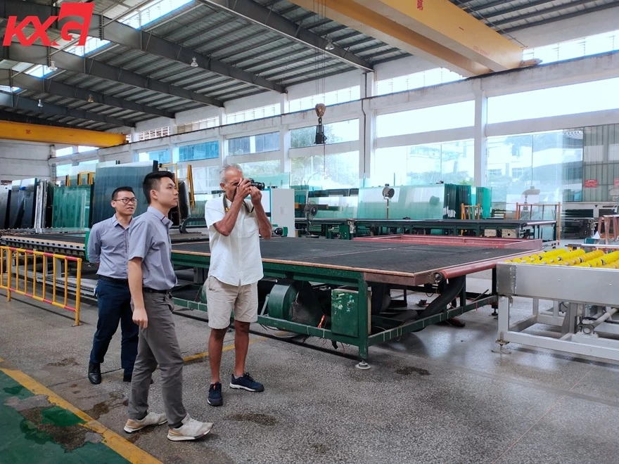 Mauritius customer visiting Kunxing glass factory and taking photo of glass cutting to size and glass edge grinding