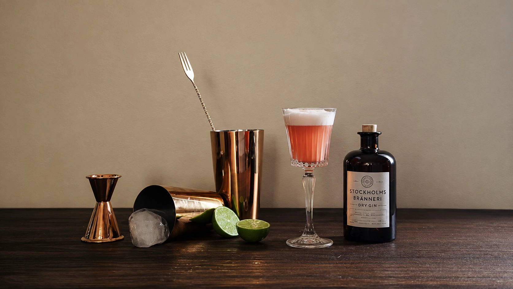 Copper cocktail shaker set with jigger, bar spoon, cocktail glass and bar tools on a wooden table
