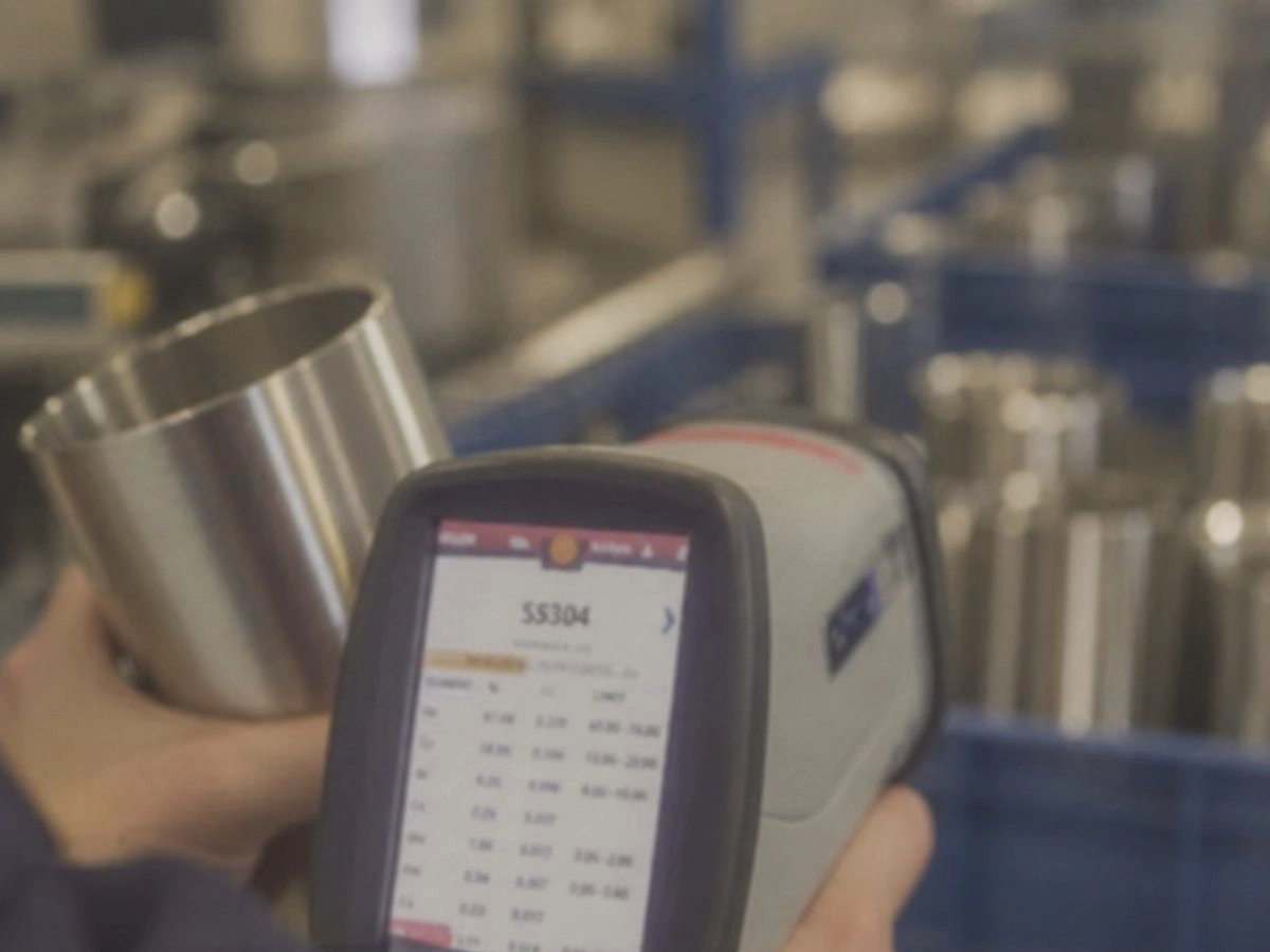 Handheld XRF analyzer confirming SS304 stainless steel grade on a cup body