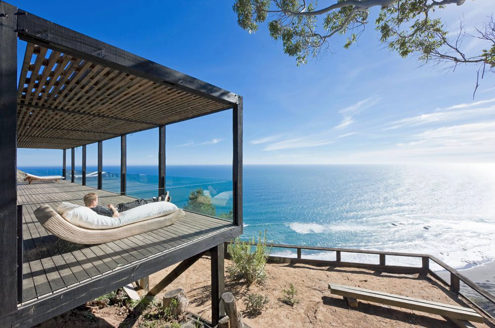 Una casa prefabricada de vidrio vinculada al cielo azul y al mar